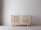 Caravan Crib in ash, mattress at the lower support height for older babies who can pull themselves up to stand.