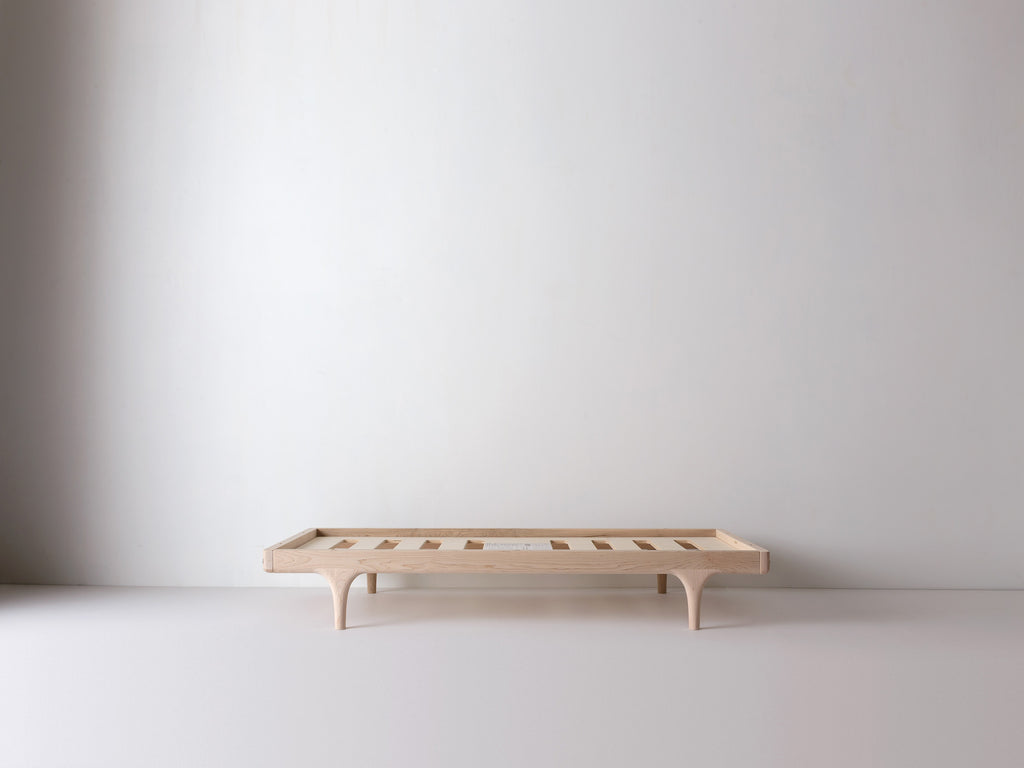 Caravan Crib base in ash in platform configuration, no mattress, visible slat supports across the frame.