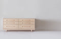 Caravan Double Dresser in ash, front view on a white studio floor, six drawers in two columns and sculpted Crib-style legs.