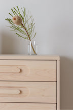 Caravan Dresser corner detail in ash, glass tumbler holding a banksia branch on top, recessed pulls on the drawer fronts.