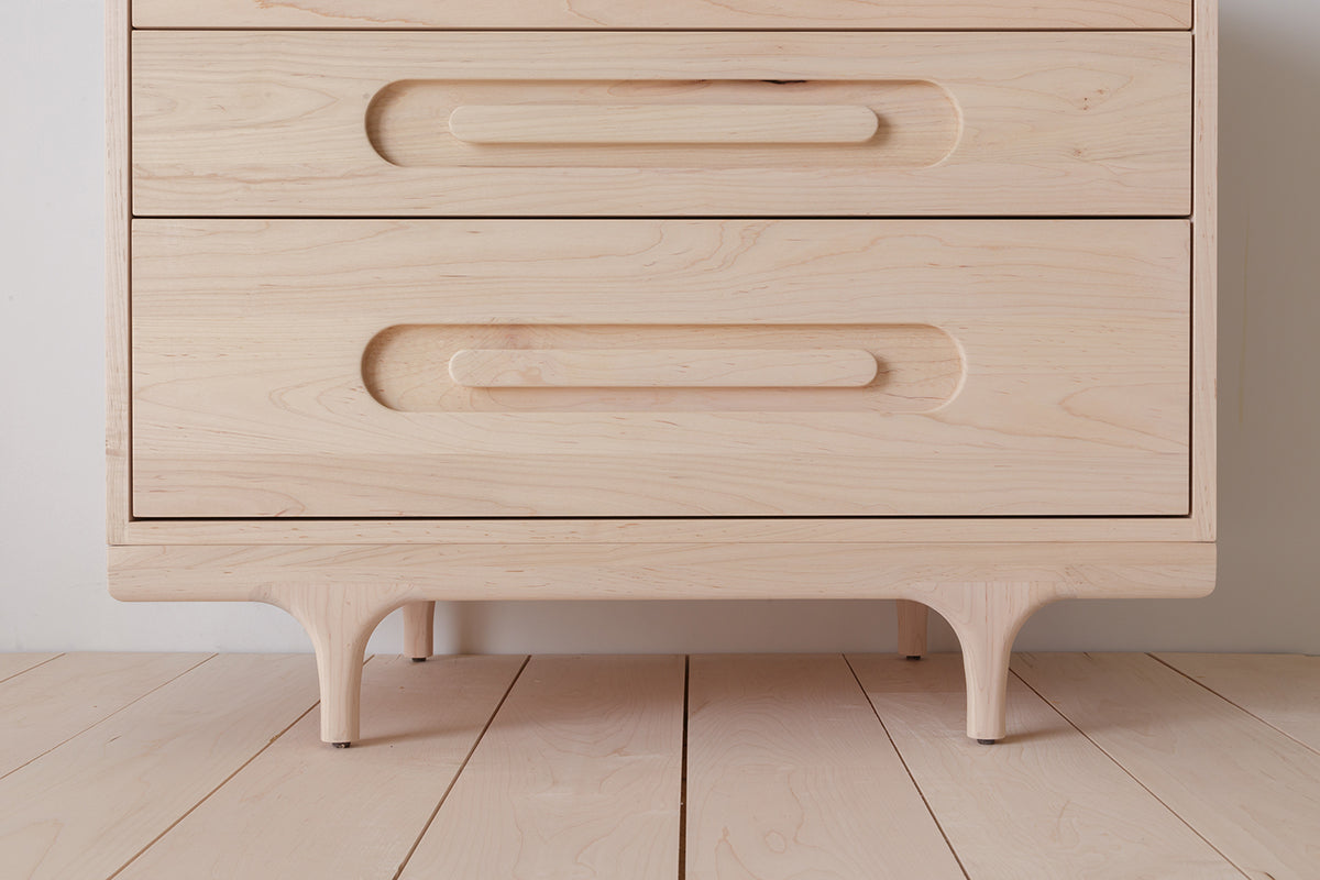 Caravan Dresser bottom corner detail in ash, the sculpted Crib-style legs and the recessed pulls on the bottom two drawers.
