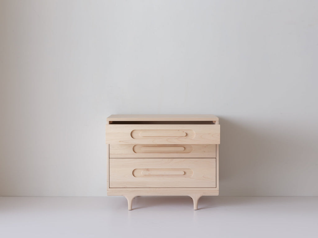 Caravan Dresser in ash with the top drawer pulled out, front view on a white studio floor showing the drawer mechanism.