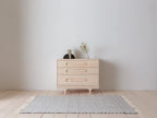 Caravan Dresser in ash on a maple plank floor with open book on a black bookend and a banksia branch in a glass vase on top.
