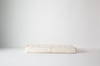 Dream No. 1 Mattress in cream organic cotton on a white studio floor, double-sided with Infant and Toddler labels visible.