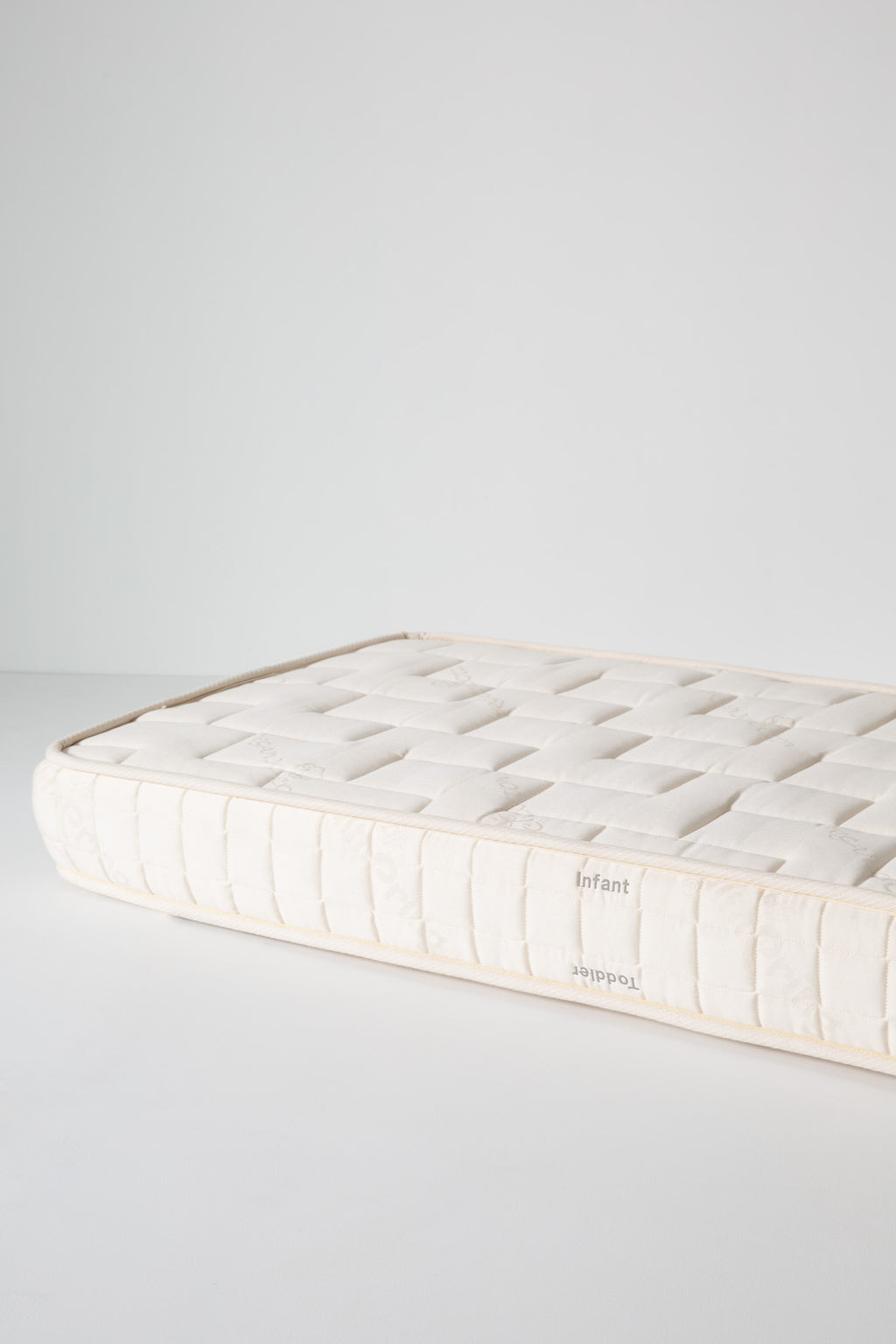 Dream No. 1 Mattress corner detail with tufted organic cotton top surface and ticking sidewall, Infant/Toddler labels.