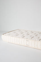 Dream No. 1 Mattress corner detail with tufted organic cotton top surface and ticking sidewall, Infant/Toddler labels.