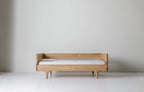 Caravan Divan in white oak with walnut corner caps, backrest configuration, mattress on the base on a white studio floor.
