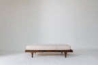 Caravan Crib in solid walnut converted to platform toddler bed, mattress on the base on a white studio floor.