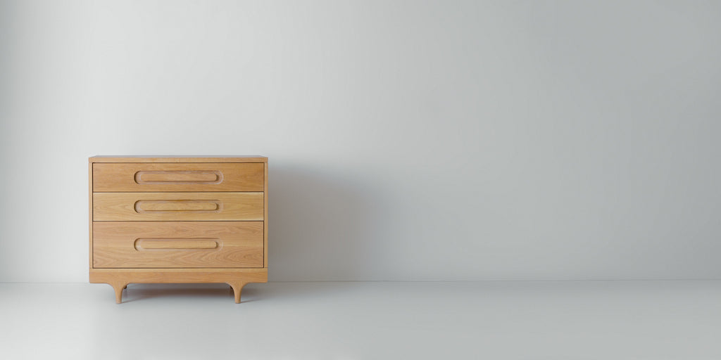 Caravan Dresser in white oak, off-center to the left in a wide format frame, white studio floor and pale grey wall.