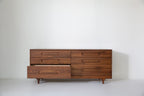 Caravan Double Dresser in walnut with the bottom-left large drawer pulled out, showing the drawer interior on a white floor.