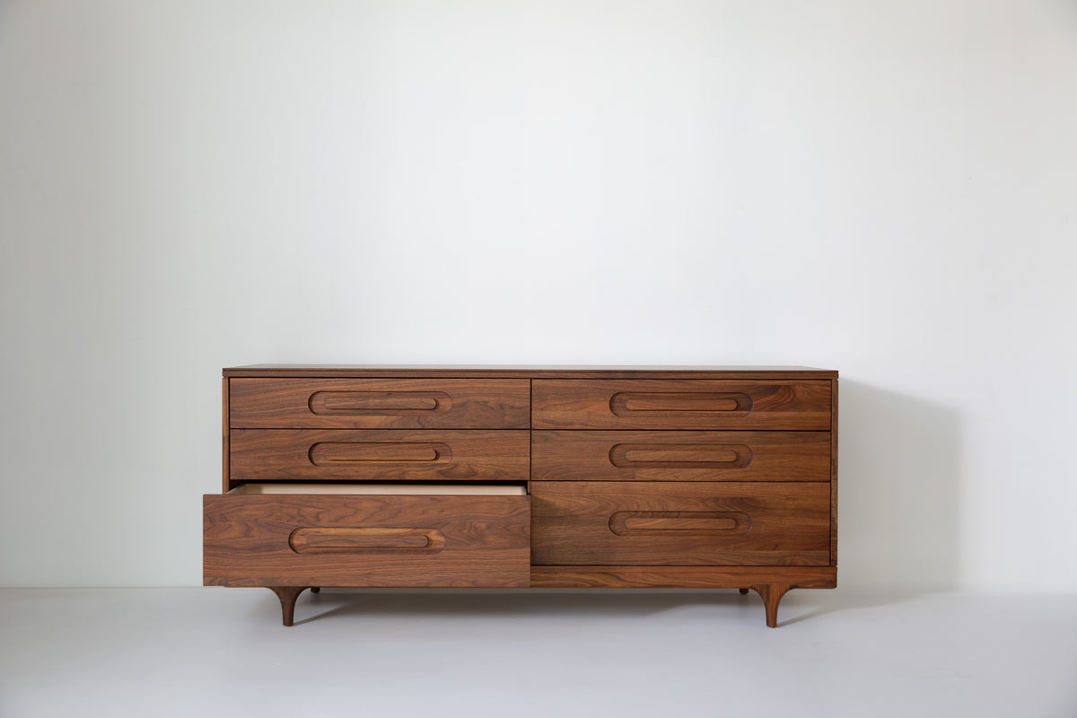 Caravan Double Dresser in walnut with the bottom-left large drawer pulled out, showing the drawer interior on a white floor.