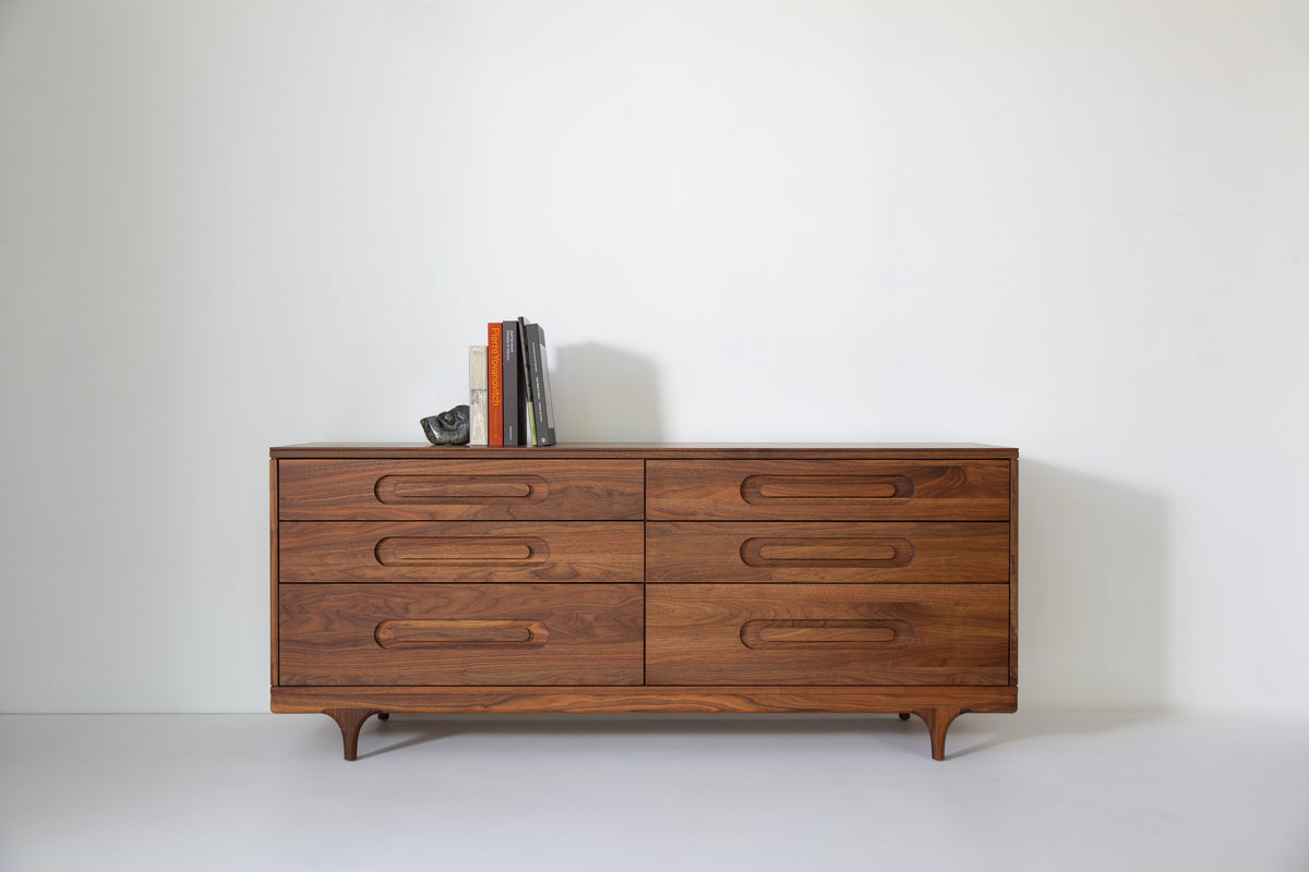 Caravan Double Dresser in walnut with stacked Pierre Yovanovitch design books and a small dark stone sculpture as bookend.