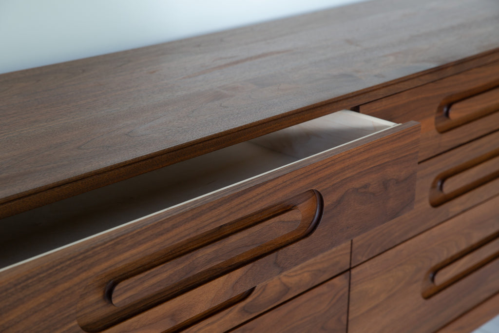 Caravan Double Dresser detail in walnut, top-left small drawer pulled open showing the carved oblong recessed pull and edge.