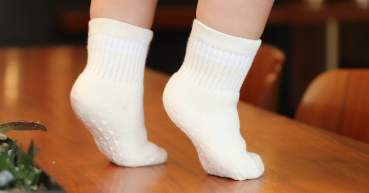 Toddler feet in Piggy's crew socks on a wooden table