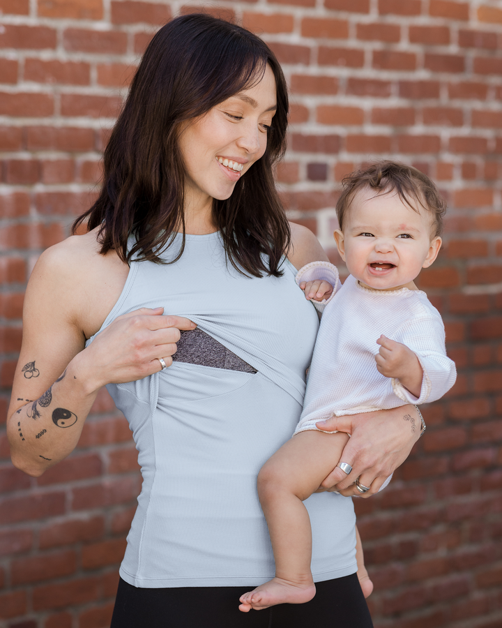 Mother in a Kindred Bravely nursing tank holding her baby