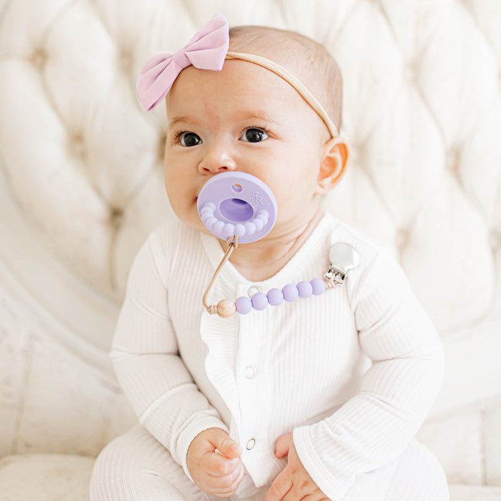 Baby with a lavender Ryan & Rose Cutie PAT pacifier and clip
