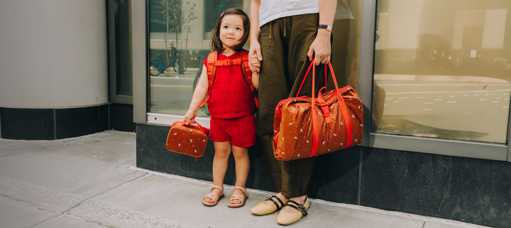 Child and parent carrying Caraa bags on a city street