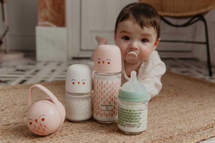 Baby with a Suavinex pacifier beside Bonhomia glass bottles