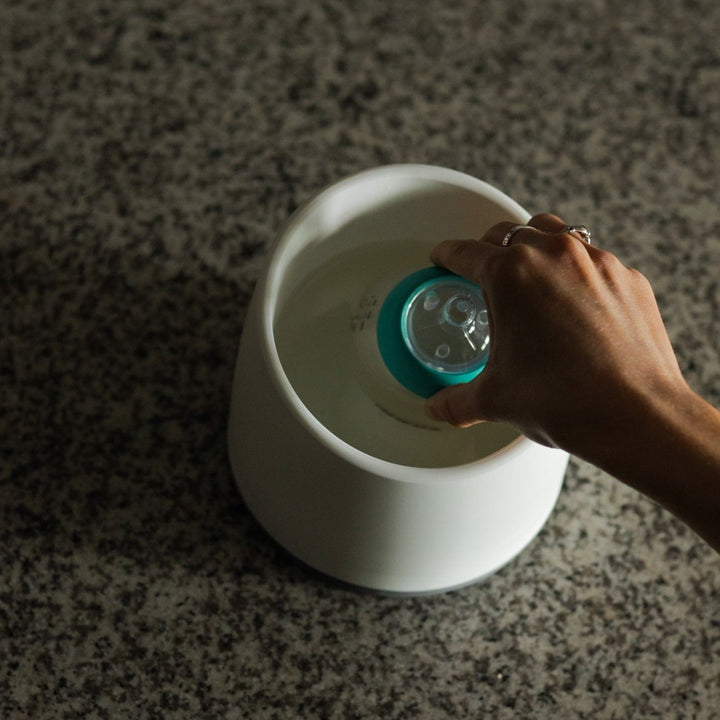 Placing a Nanobébé breastmilk bottle into the warming bowl