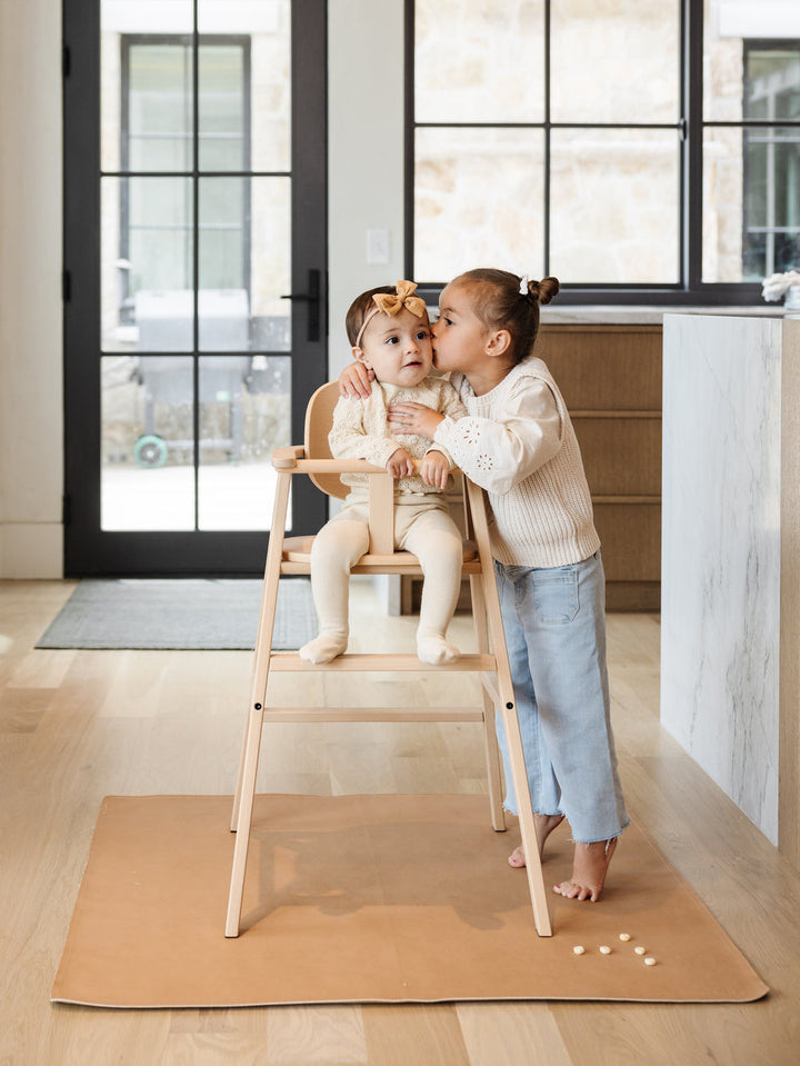 Gathre — Baby in highchair with sibling kissing them on the cheek.