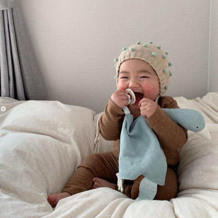 Laughing baby holding a Saga Copenhagen cuddle goose