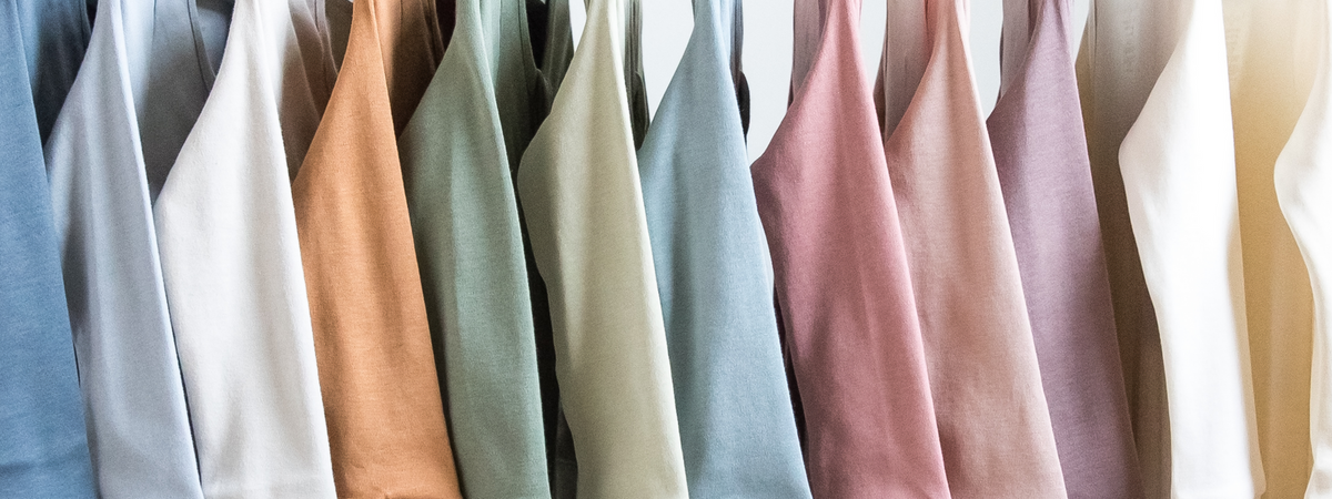 Colored Organics organic cotton tees in soft colors hanging on a rail