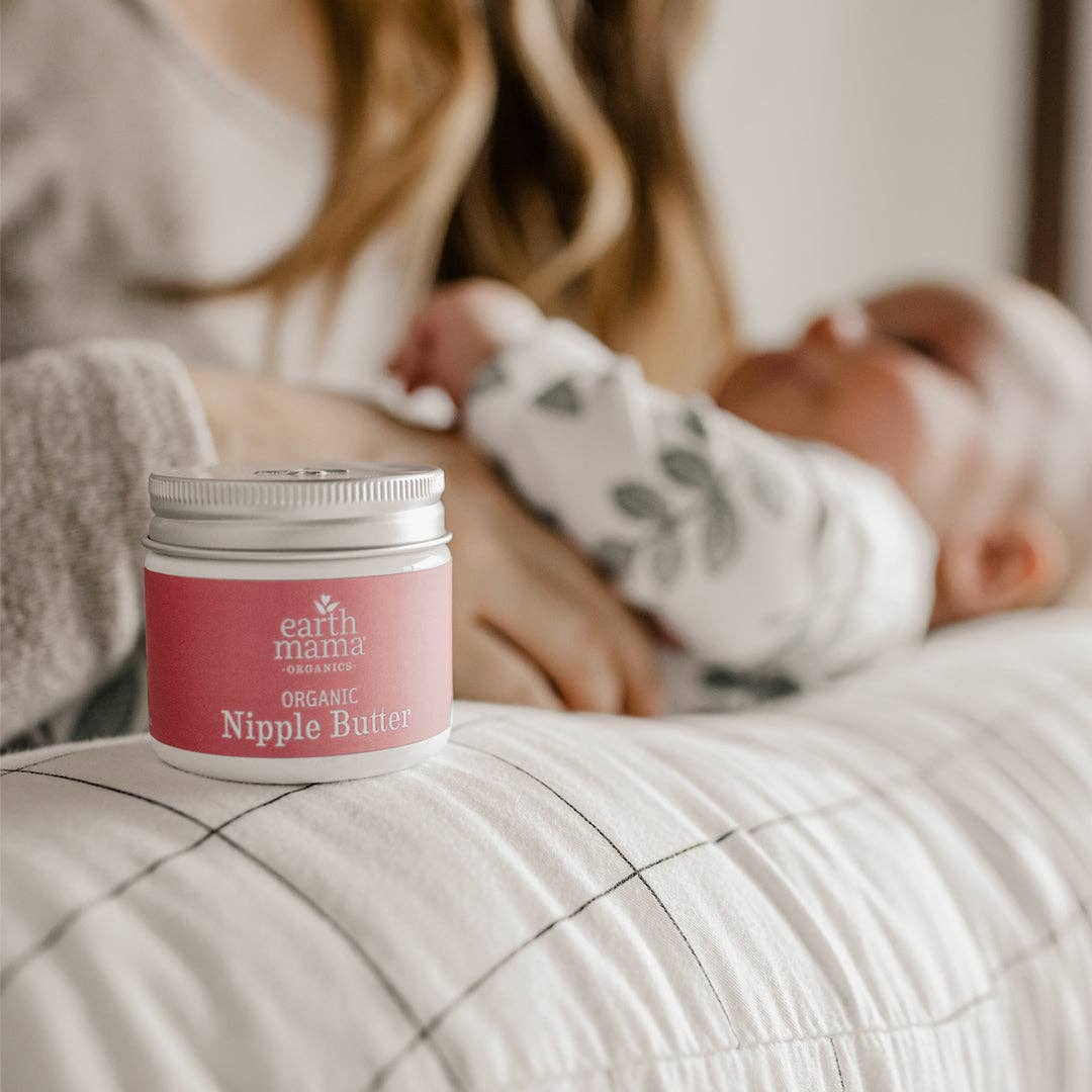 Earth Mama Organic Nipple Butter jar beside a sleeping baby