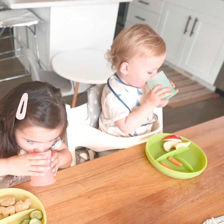 Olababy — A toddler in a high chair drinking from a mint silicone cup, an older girl at the same table holding
