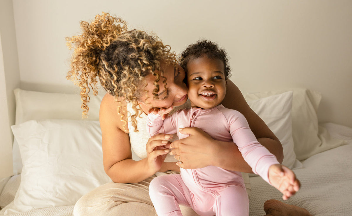 Mother and baby in Kindred Bravely bamboo pajamas on a bed