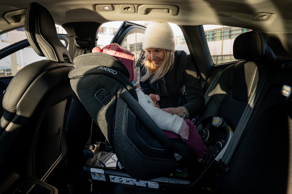 Parent buckling a child into the Axkid ONE 3