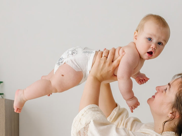 Parent lifting a baby in a Parasol diaper overhead